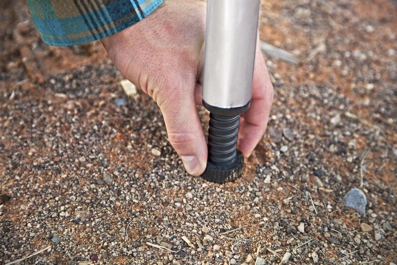 A portable mountaineer using the Camp Chef Mountaineer Camp Stove Leg Kit with a pole in the dirt.
