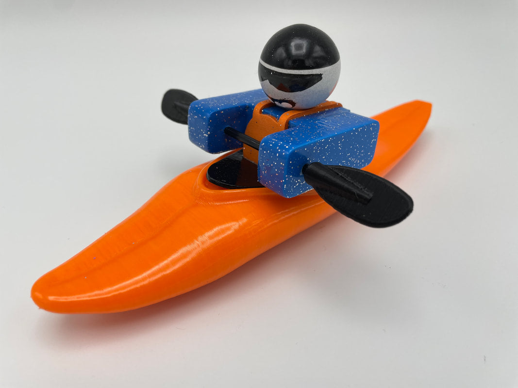 Foamie Friends presents the Foamie Mini Slice: a toy figure in a kayak featuring blue flotation devices and black paddles, highlighting an advanced hull design for optimum performance, set against a plain white background.