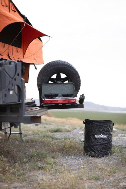 A camper trailer with a Camp Chef Collapsible Garbage Can-compliant camp kitchen on top of it.