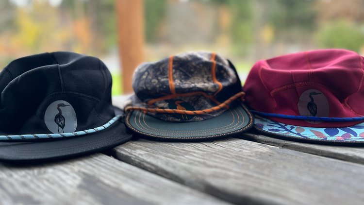 Three Nobdody Flat Brim Skull Caps sitting on a wooden table, made by Nobdody's.