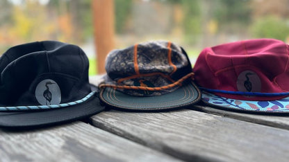Three Nobdody Flat Brim Skull Caps sitting on a wooden table, made by Nobdody's.