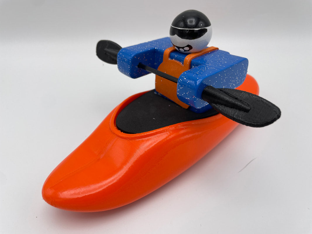 The Foamie Play Boat from Foamie Friends smoothly rides the currents in a blue and orange kayak, expertly maneuvering black paddles while sporting a helmet and sunglasses. Ideal for discovering river dynamics, this play boat adventure promises endless fun.
