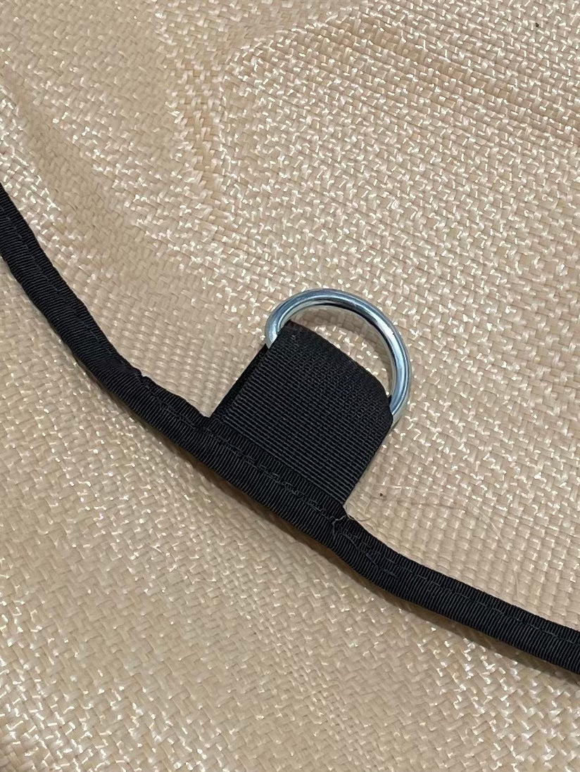 A silver metal d-ring attached to a black strap, laid across a textured beige Over It Raft Covers raft cover.