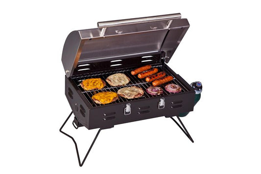 A Camp Chef Portable BBQ Grill with a variety of foods on it, boasting 12,000 BTU.