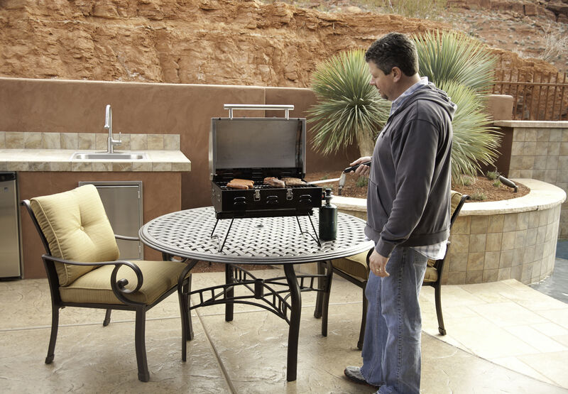 A man grilling on a Camp Chef Portable BBQ Grill.