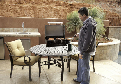 A man grilling on a Camp Chef Portable BBQ Grill.
