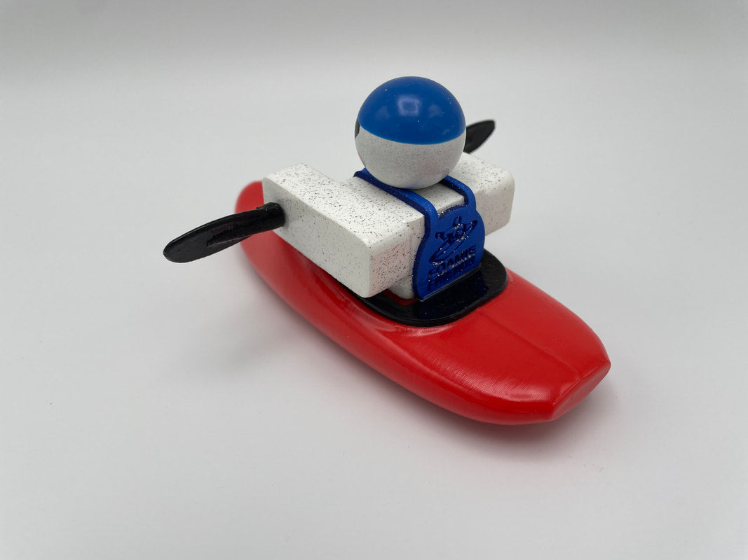 The Foamie Friends Foamie Mini Playboat features a toy figure equipped with a blue helmet and life jacket, highlighting its remarkable hull design as it rests in a red kayak with black paddles, making it perfect for miniature play on any backdrop.