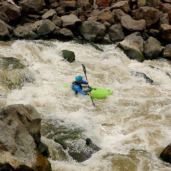 a man riding a green kayak on top of a river.