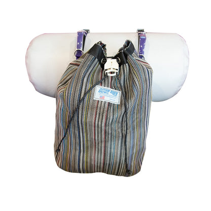 A Thwart Bag by Down River Equipment, featuring a striped UV-resistant, quick-access cinching system, hangs on a pole with a purple and white polka dot cushion behind it.