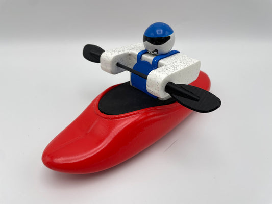 A Foamie Play Boat figure from Foamie Friends skillfully maneuvers river dynamics with a black paddle, dressed in a blue and white outfit and wearing a sturdy blue helmet.