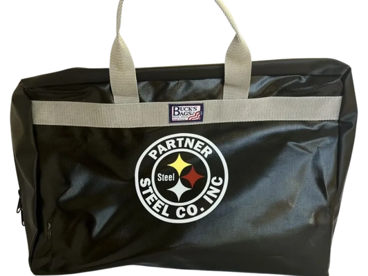 A large black bag with gray handles, featuring a circular logo of "Partner Steel" and another patch displaying "Durable custom sized Buck's Bags" to protect the Stove Bags.