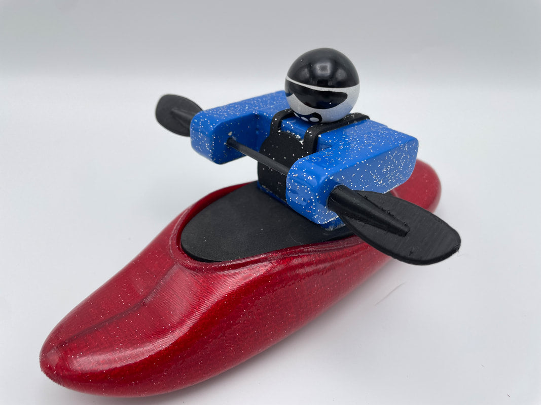 Foamie Play Boat figure by Foamie Friends, featuring a character in a red kayak with a black helmet and blue jacket, holding a paddle against a plain background.