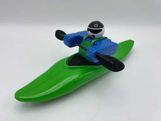 The Foamie Friends Foamie Half-Slice is a toy figurine of a kayaker featuring a green kayak, dressed in a blue outfit, and holding a black paddle. It beautifully captures the thrill of river play and showcases intricate water dynamics.