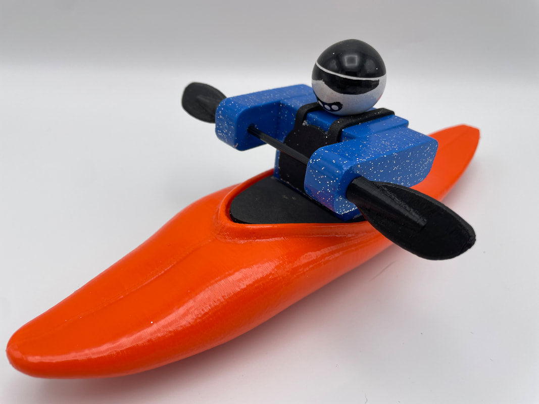 A Foamie Friends Foamie Half-Slice toy figure, dressed in blue gear and seated in an orange kayak with black paddles, is ready for river play.