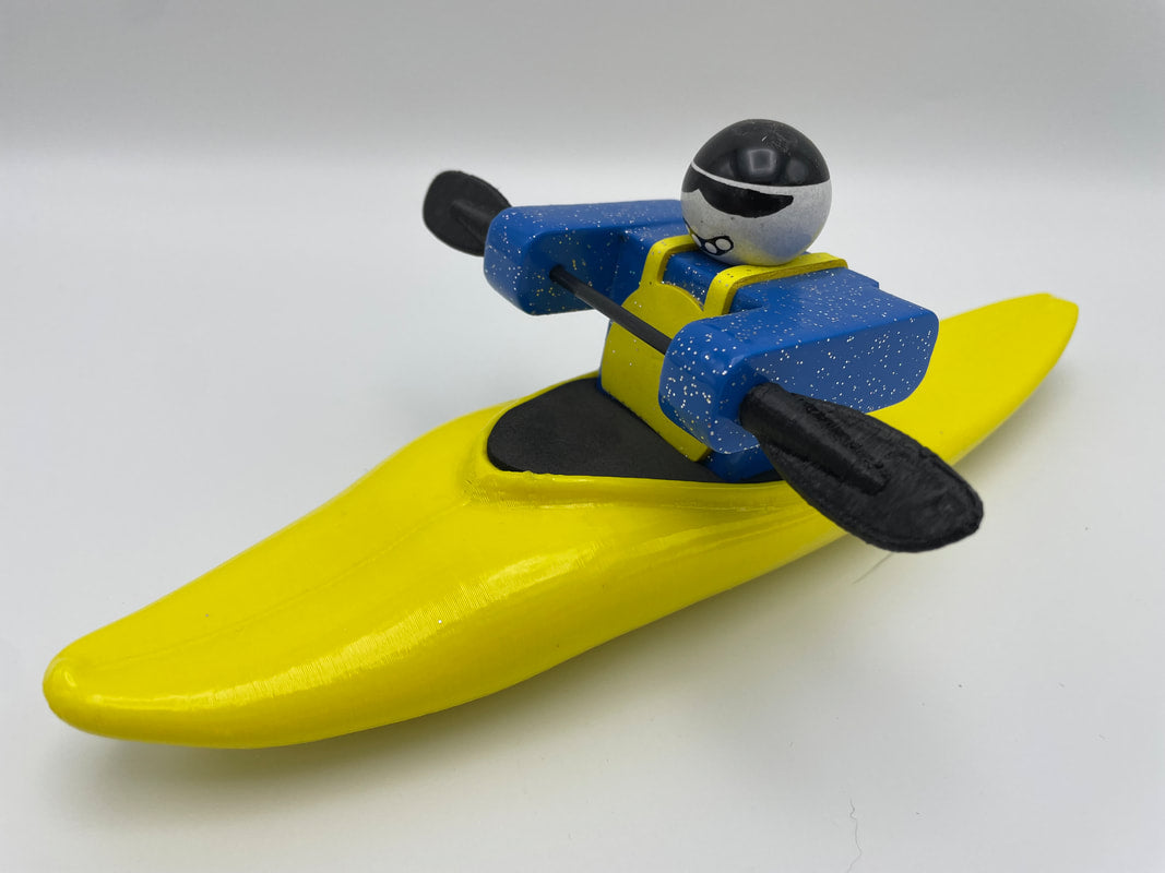 The Foamie Half-Slice, a toy figure from the Foamie Friends series, skillfully navigates river play in a yellow kayak with blue details, wearing a helmet and sunglasses that showcase its exceptional water dynamics.