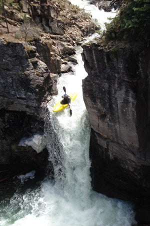 a man is kayaking down a waterfall.
