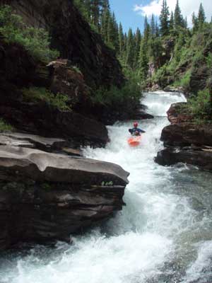 a man is kayaking down a rapid river.