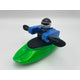 The Foamie Friends Foamie Spud Play Boat features a toy figure in a green kayak, capturing the excitement of river sports. Equipped with a black paddle and dressed in a coordinating blue and black outfit with helmet, this character is primed for adventure.