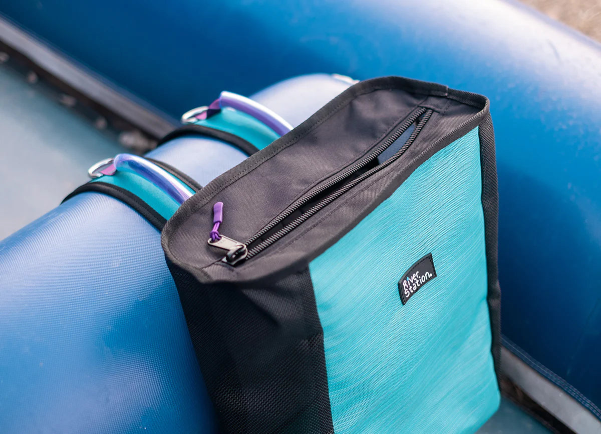 A teal and black River Station Gear mesh thwart backpack for hikes with a YKK zipper on a blue seat.