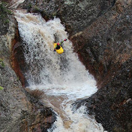 a man is kayaking down a waterfall.