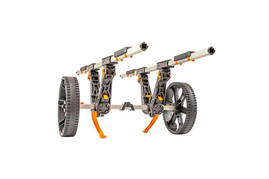 The YakAttack TowNStow BarCart Kayak Cart features two large wheels, adjustable bunk-style uprights on parallel rails, and orange supports made of black, grey, and orange plastic, pictured against a white background.