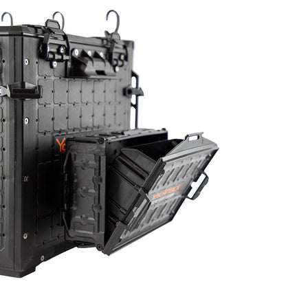 A YakAttack TracPak with PicPocket QuickDraw in black is wall-mounted, shown with its box open to reveal the hinged lid and interior compartment.