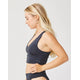 Woman with long blonde hair wears the Carve Tofino Top by Carve with matching bottoms, standing in profile against a plain light background.