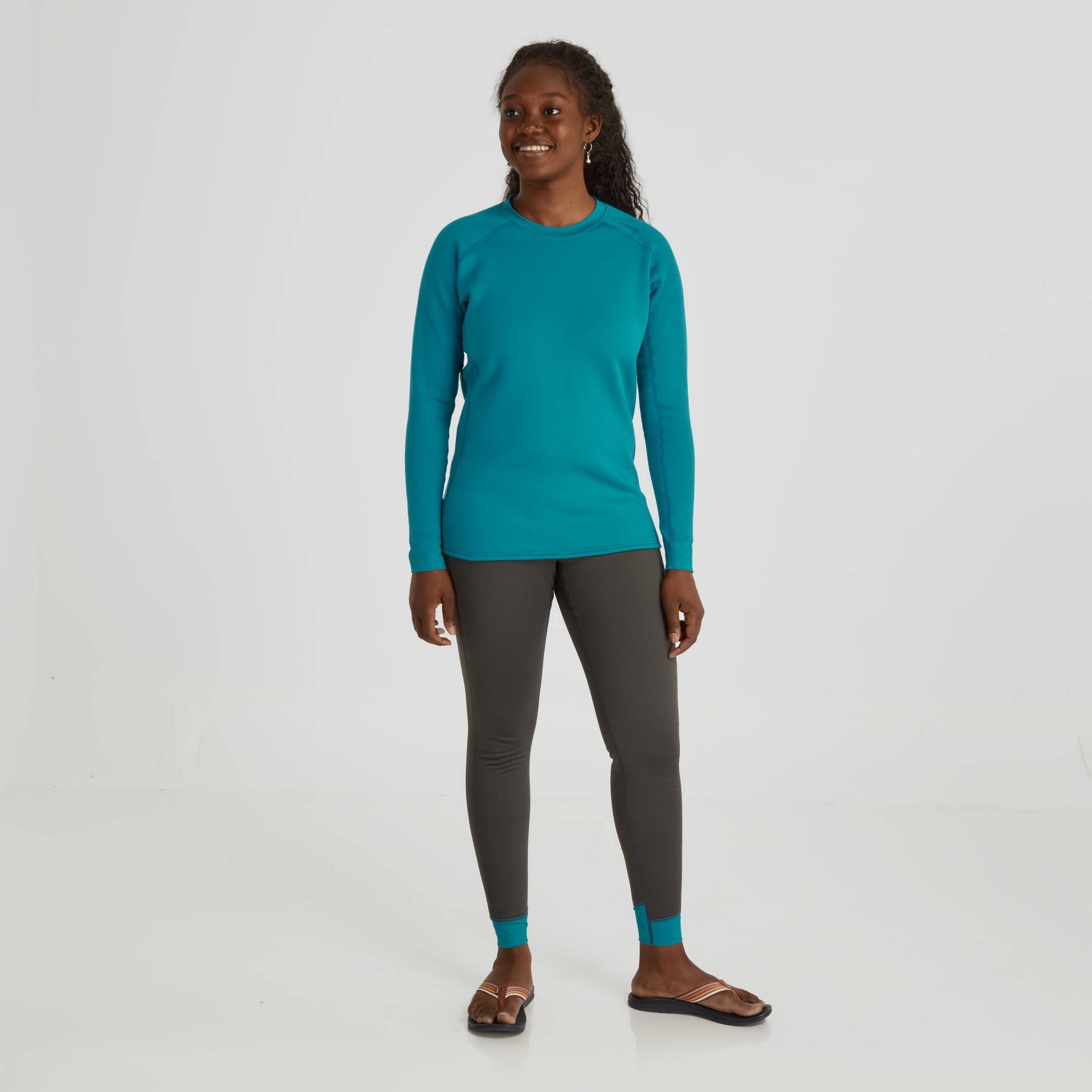 A woman wearing an NRS Expedition Weight Shirt - Women's for warmth and enhanced mobility, paired with grey leggings.