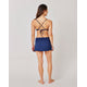 A woman wears the Carve Hoku Swim Skirt, featuring an adjustable hem and built-in bikini bottom, paired with a navy blue criss-cross back bikini top.
