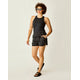 A person with curly hair wears sunglasses, a black sleeveless top, Carve's Rhett Stitched Shorts, black sandals, and accessories, standing against a plain light background.