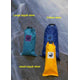Three waterproof stow bags: a large turquoise kayak stow, a blue Canoe Stow by Jacks Plastic Welding crafted from PVC-coated polyester, and a small yellow kayak stow, all strategically placed on the rocky surface.