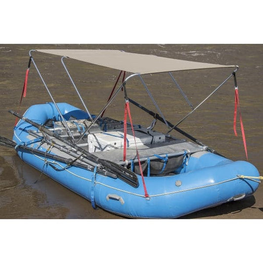 A blue inflatable raft with a marine fabric canopy in the Coyote River Gear Raft Bimini style sits on sand. The metal frame supports the cover, red straps offer contrast, and oars are secured at the sides.