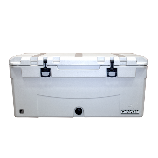 The Navigator Pro 150 Raft Cooler by Canyon Coolers is a large white rotomolded cooler with durable black latches and a convenient bottom left drain plug, featuring the "Canyon" logo on the lower right and backed by a lifetime warranty.