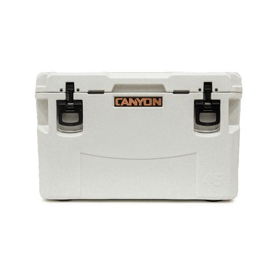The Canyon Coolers PRO Series white hard-sided cooler, featuring the "Canyon" logo and two black latches, offers maximum ice retention and comes with a lifetime warranty.