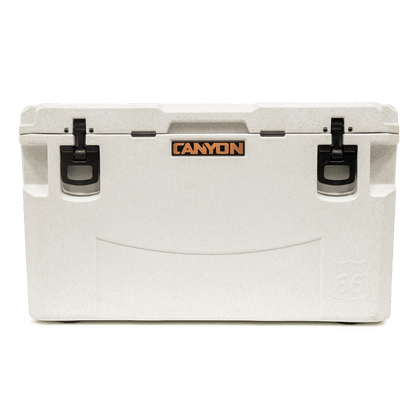 The PRO Series Coolers by Canyon Coolers, with black latches and side handles, display the brand's logo on the front. Engineered for maximum ice-retention, they offer reliable performance and come with a lifetime warranty.