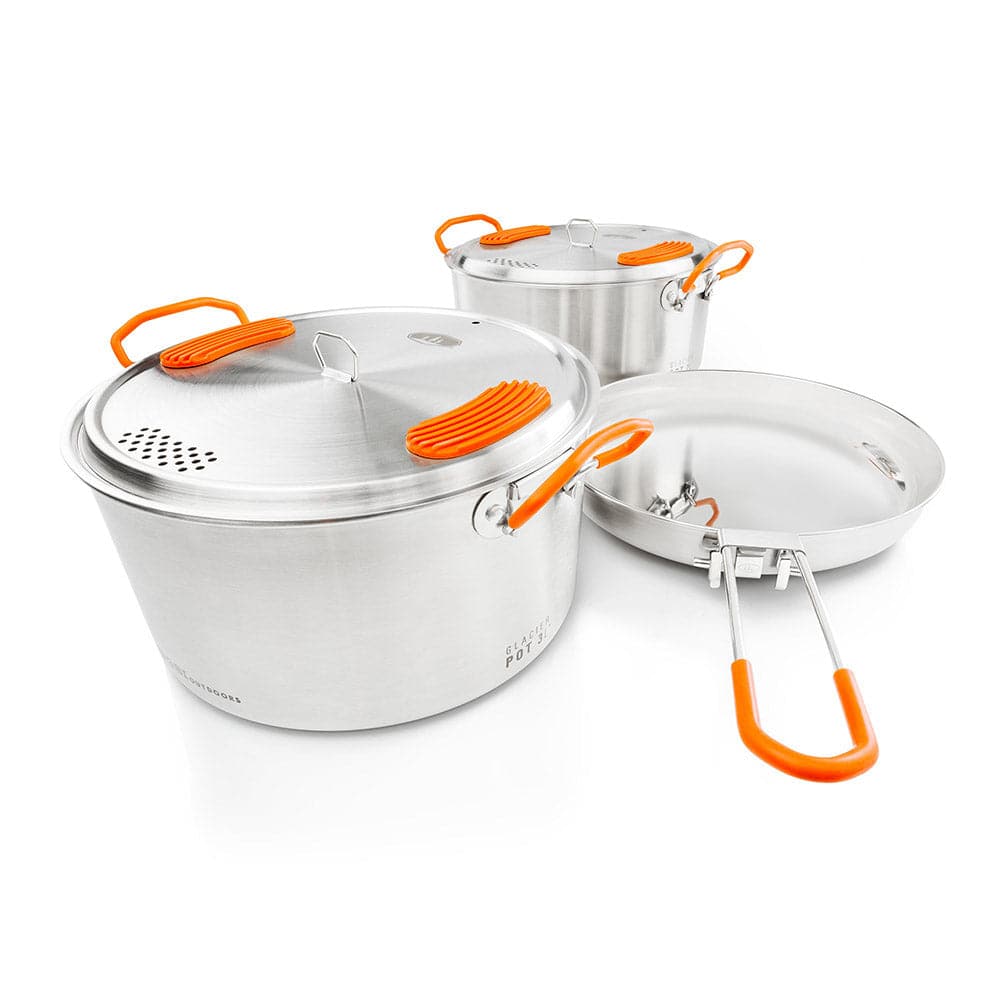 Experience the ideal mix of durability and style with the GSI Outdoors Glacier Base Camper cookware, featuring three stainless steel pots and pans with vibrant orange handles and knobs, perfect for gourmet cooking adventures.