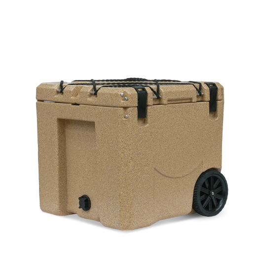 The Canyon Coolers Mule 30 Cooler in tan has strong hard wheels, black handles, and clasps. It includes a front spout for easy draining, perfect for outdoor adventures.