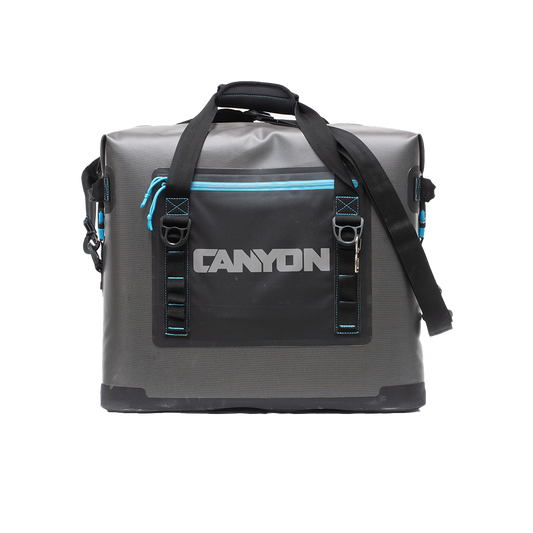 The Canyon Coolers Nomad Series Soft Cooler is a gray and black duffel bag with "Canyon" printed on the front, featuring blue accents, a waterproof zipper, two handles, and an adjustable shoulder strap, crafted for any adventure.
