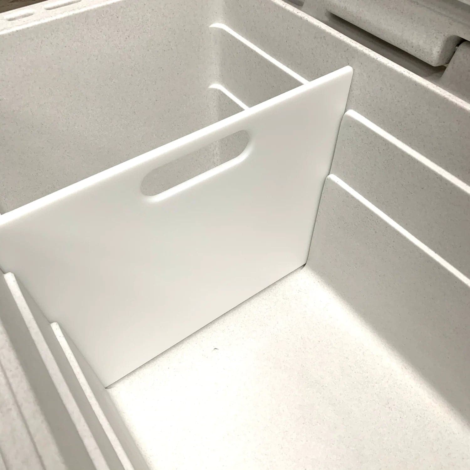 The Canyon Coolers Navigator 150 Divider is a white, BPA-free cooler divider designed to fit inside a gray storage bin with grooves for adjustable positioning.