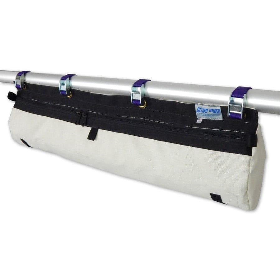 The beige and black Cross Bar Bag XD by Down River Equipment is long and cylindrical, hanging from a metal bar with three blue straps. It has a zipper on top for easy access to your cargo gear.